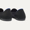 Close up of the heel of The Daily Loafer in Black, with raised peg outsoles and Rothy's signature blue halo. 
