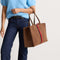 hover | The Classic Tote in ReVelvet Cinnamon Stripe, worn over the shoulder by a model, shown from the side.