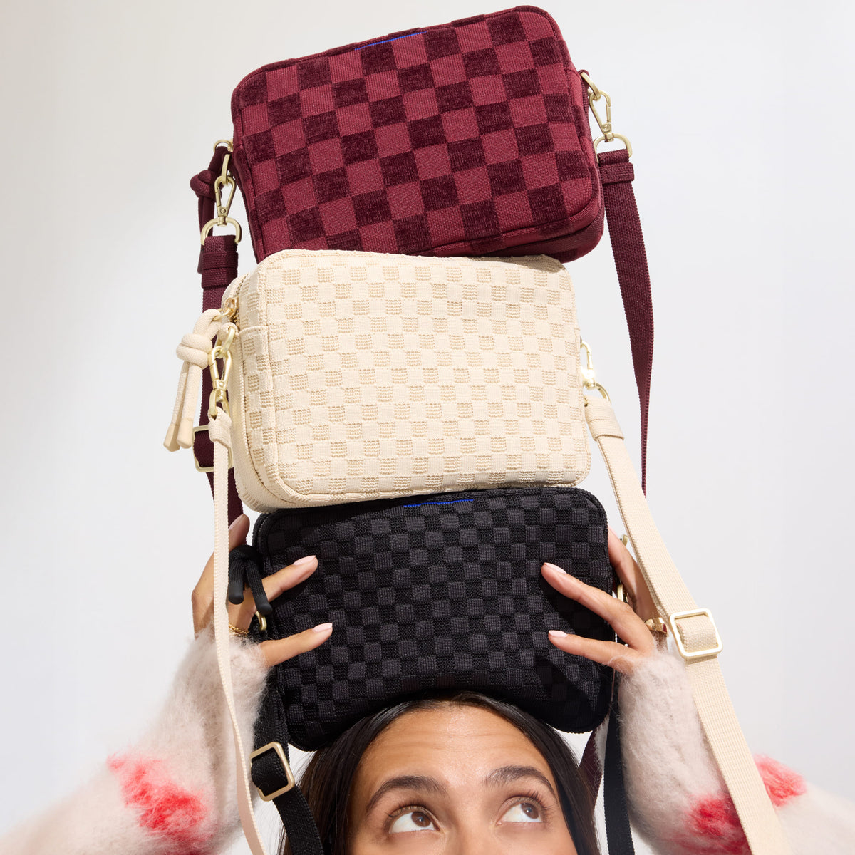 Model holding on her head The Crossbody Camera Bag in Black Sand, Sesame, ReVelvet™ Cab.